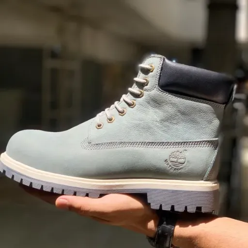 نیم‌بوت تیمبرلند (Timberland) - چرم اشبالت طوسی با لبه بالایی مشکی، دوخت دور و زیره عاج‌دار | مستر کوالیتی