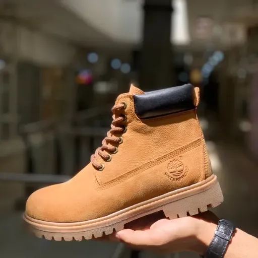 نیم‌بوت تیمبرلند (Timberland) زنانه - چرم اشبالت خردلی/عسلی با لبه بالایی مشکی، دوخت دور و زیره عاج‌دار | مستر کوالیتی